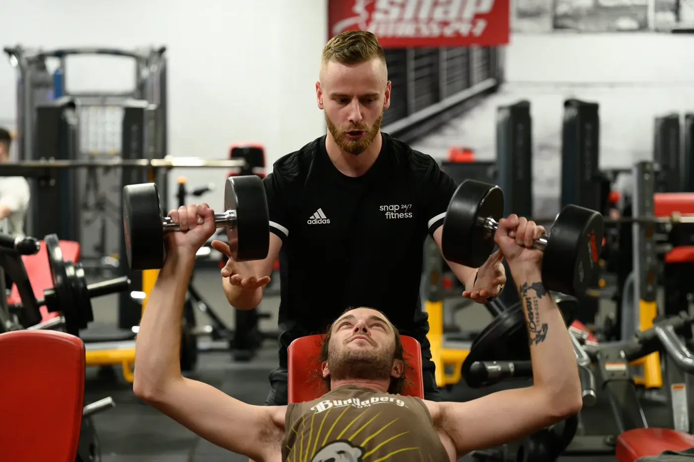 Jamie spotting a client's dumbbell press